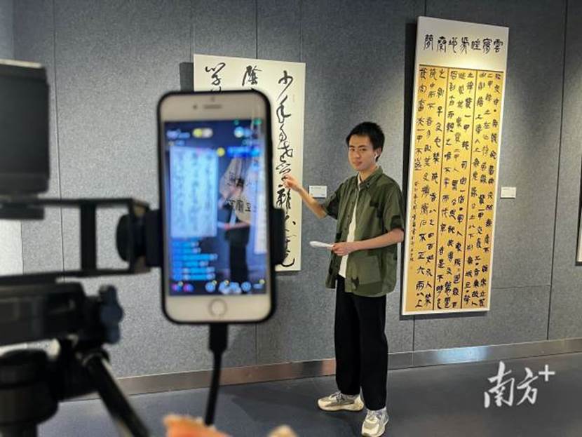 广州新华学院师生艺术作品展在省文化馆展出，网络与新媒体专业学生对师生艺术作品进行直播介绍。